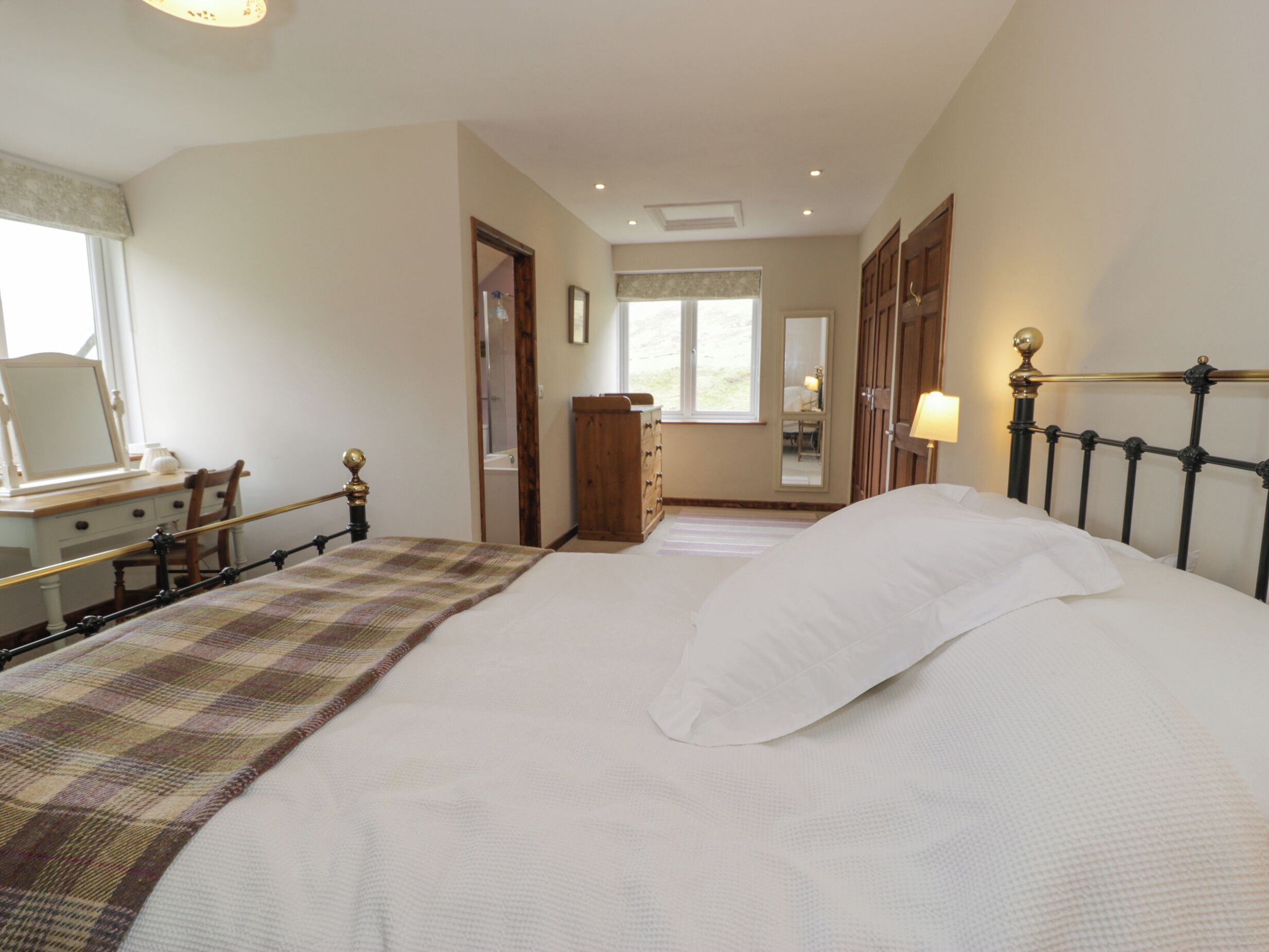 A bedroom with a bed, a dresser, a mirror, and a window.