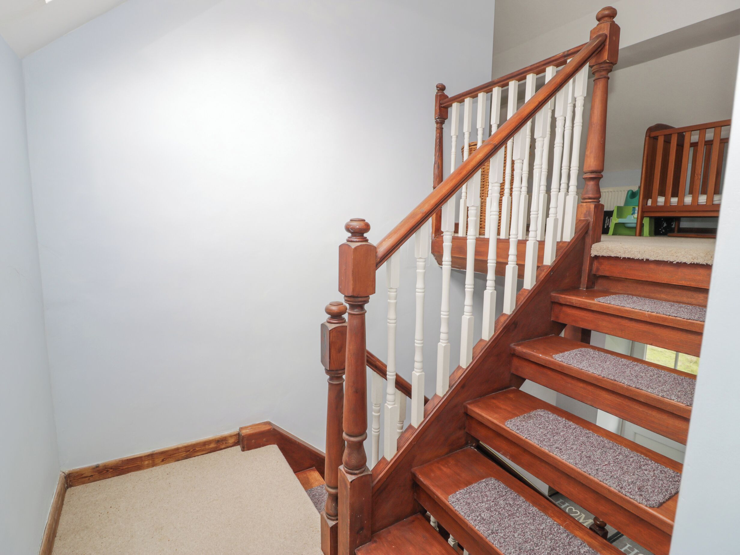 Un escalier en bois avec des balustrades blanches et des marches recouvertes de moquette.
