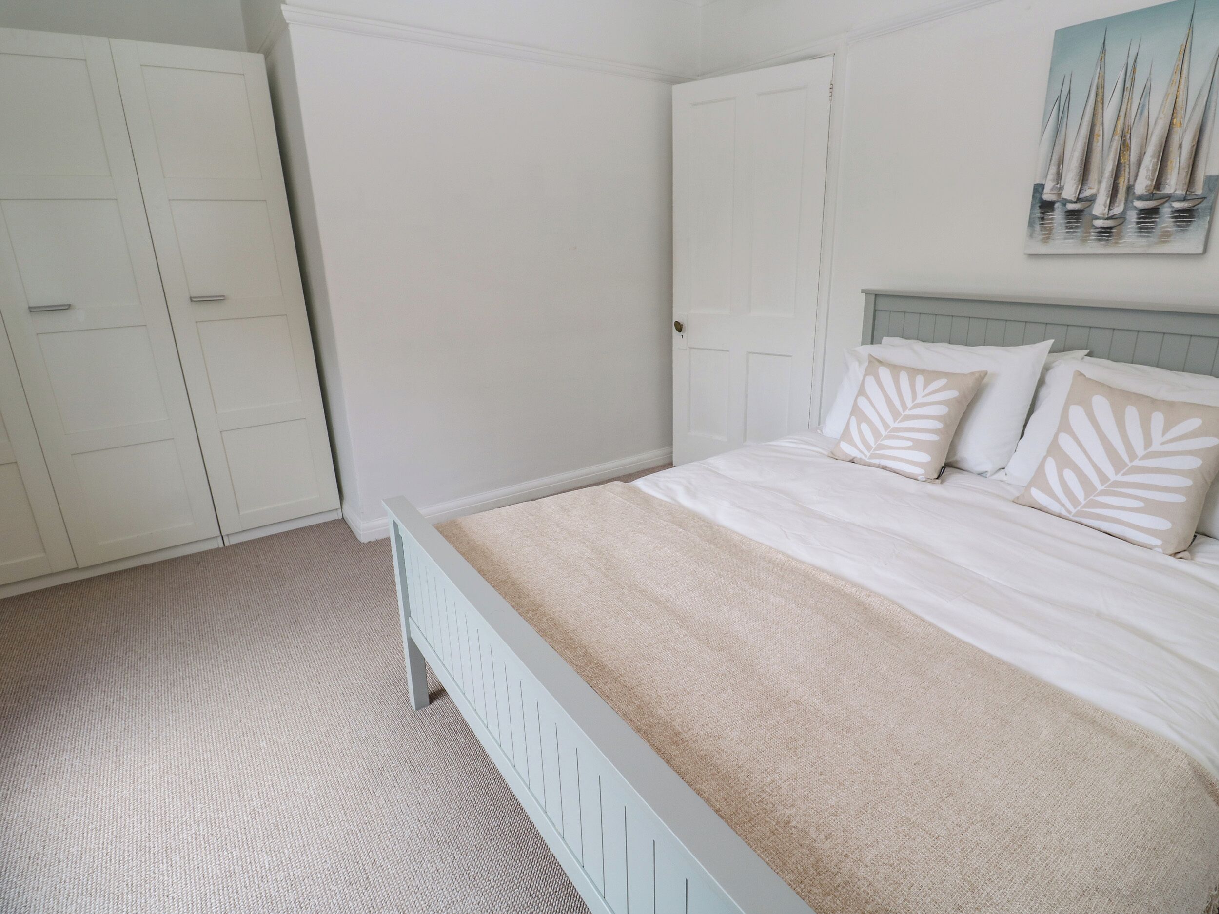A bedroom with a bed, a wardrobe, and a painting on the wall.