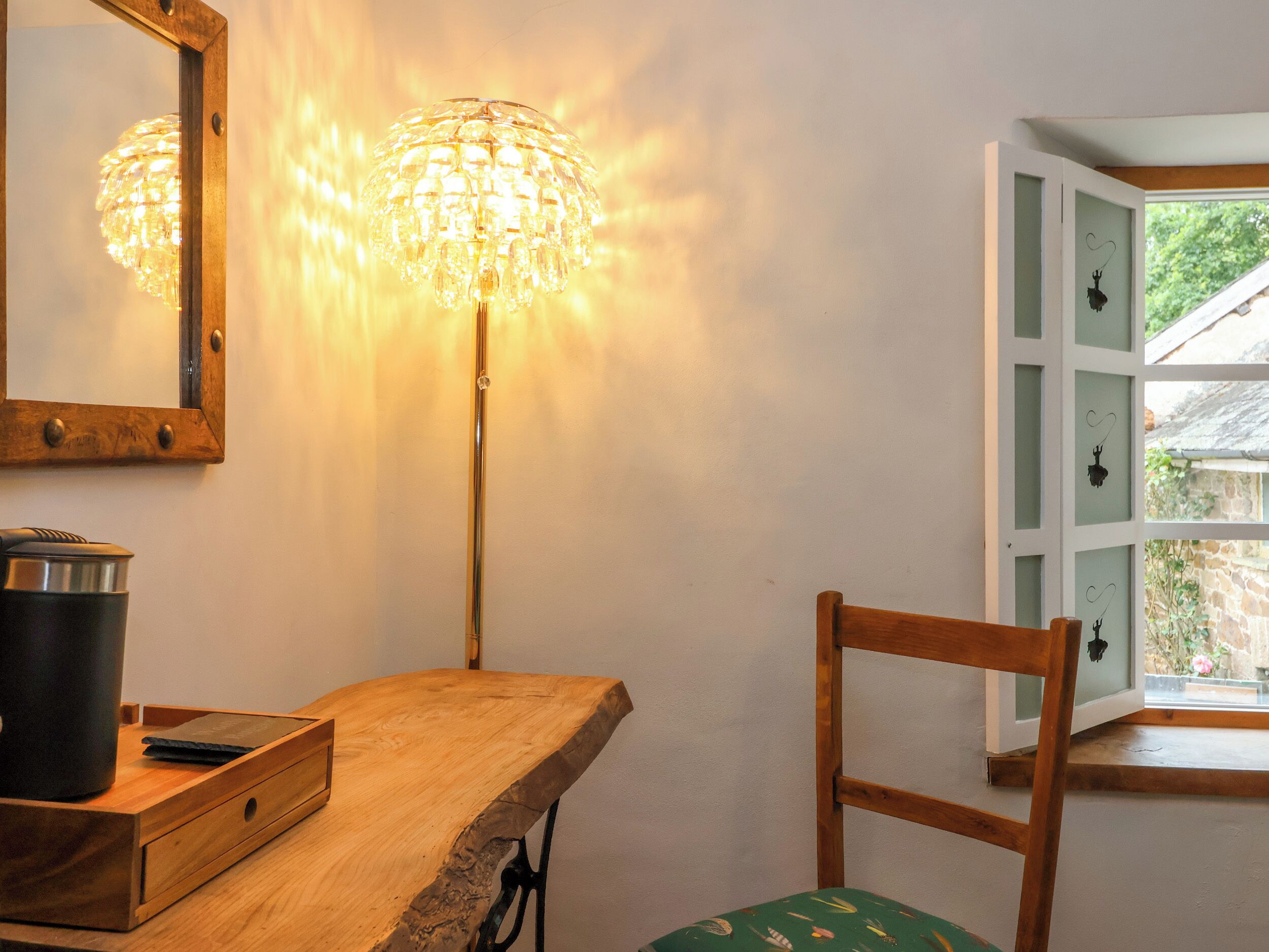 Un bureau en bois, une lampe, une chaise et une fenêtre donnant sur un paysage verdoyant.