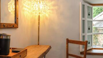 Un bureau en bois, une lampe, une chaise et une fenêtre donnant sur un paysage verdoyant.