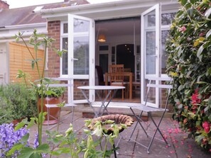 An open patio with a table and chairs, a potted plant, and a bird feeder.