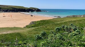 A coastal beach with a sandy shore, grassy areas, and rocky outcrops. - 2 Boathouse Terrace (Wadebridge)