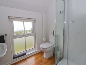 Une salle de bain comprenant des toilettes, une douche à parois de verre, une fenêtre avec vue et un porte-serviettes.