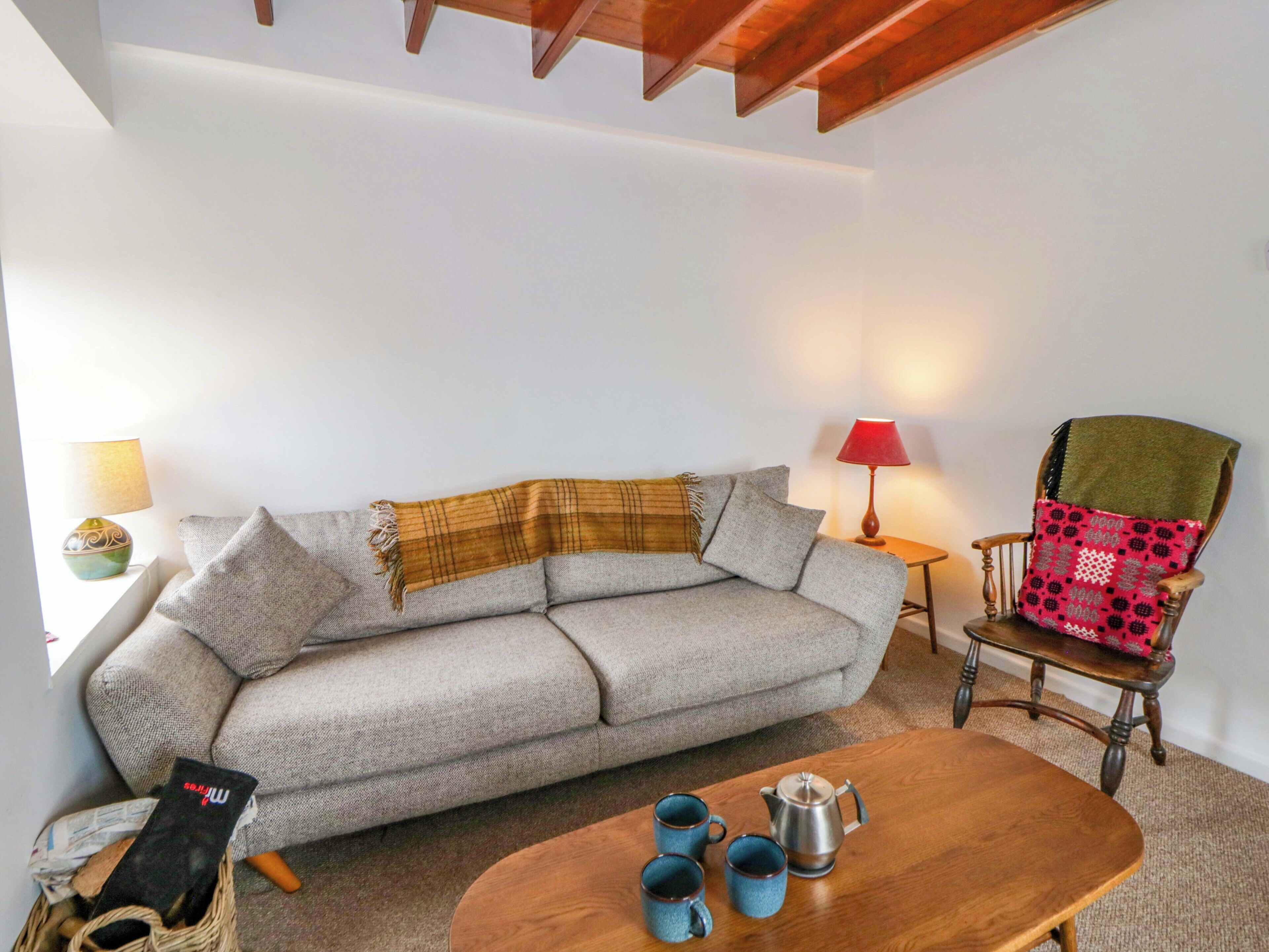 Un salon avec un canapé, une table basse en bois, un fauteuil et une lampe.