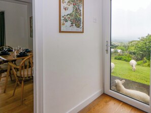 A room with a dining table set for four, a door leading outside, and a framed map on the wall. - Ceunant (Newport)