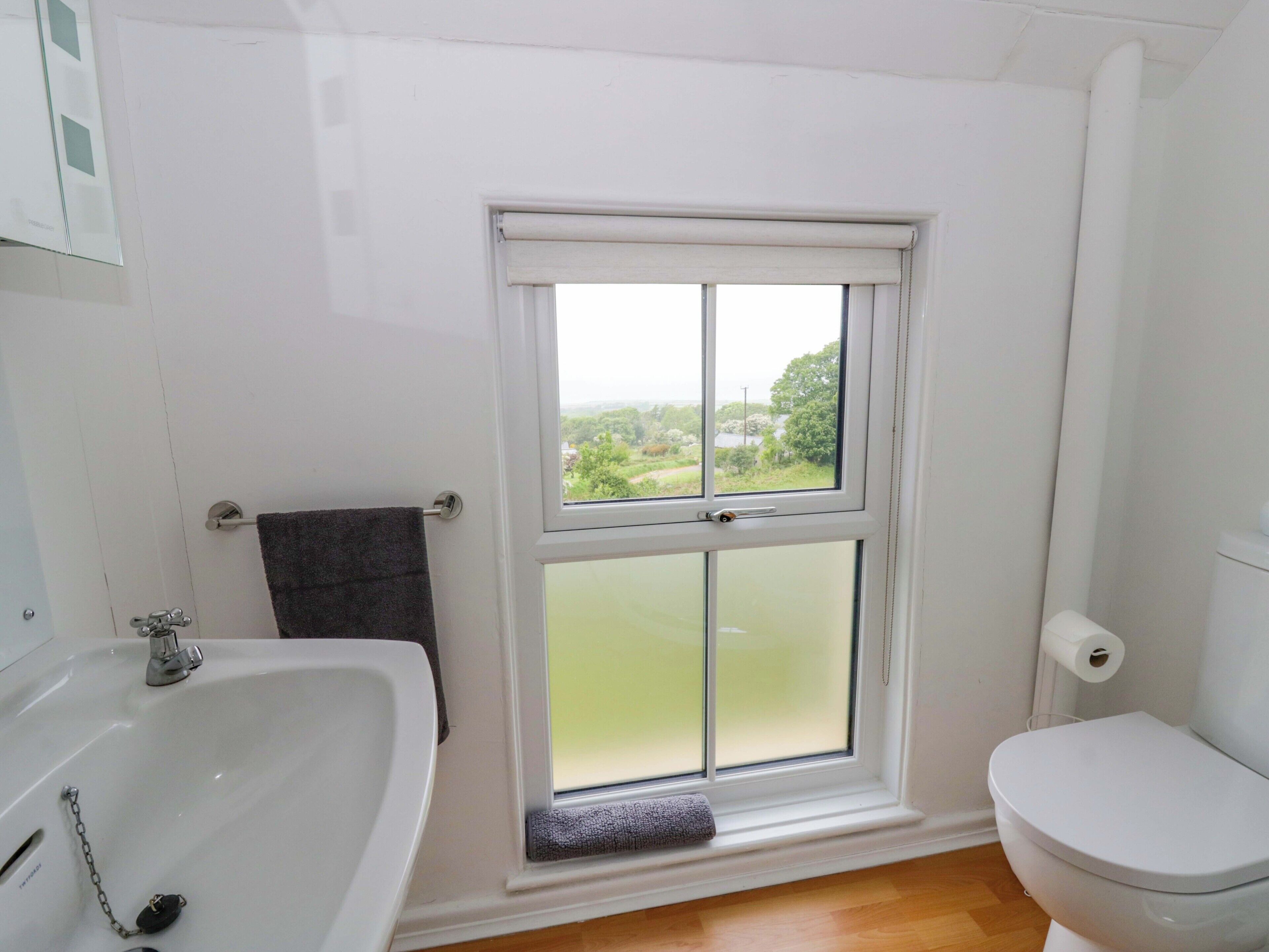A bathroom with a window, a sink, a toilet, and a towel rack.
