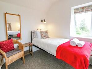 Une chambre avec un lit simple, une chaise, une table de chevet, un miroir et une fenêtre donnant sur un paysage agréable.
