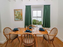 Una mesa de comedor con sillas, una ventana con cortinas y un cuadro en la pared.