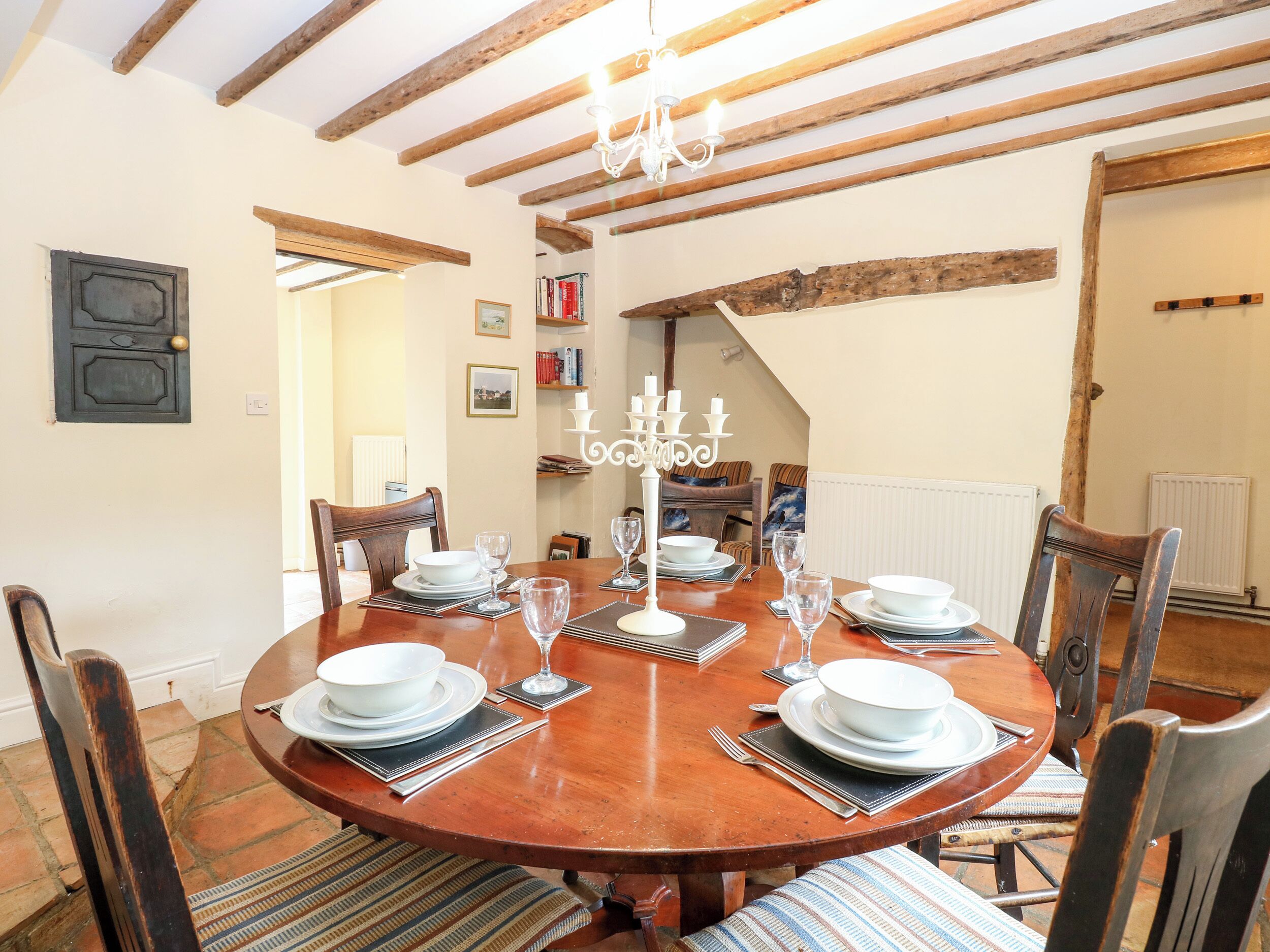 Un coin repas avec une table ronde en bois, dressée pour quatre personnes, entourée de chaises.