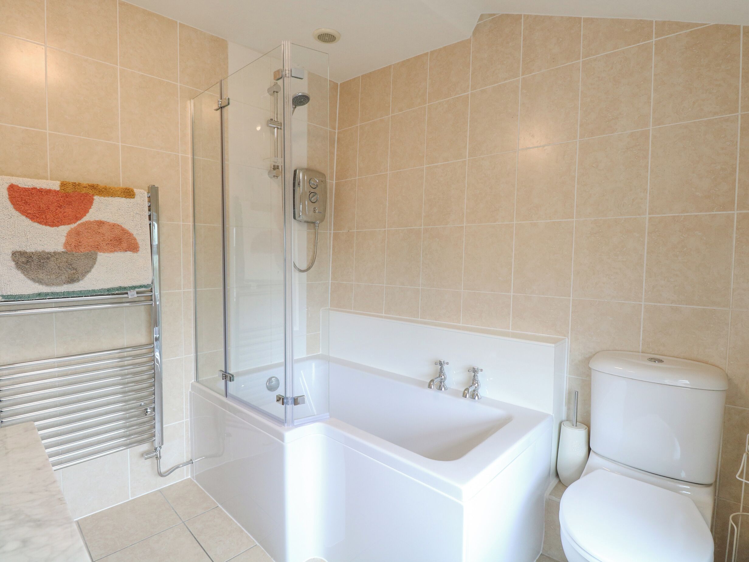A modern bathroom with a glass-enclosed shower, a white bathtub, and a toilet.