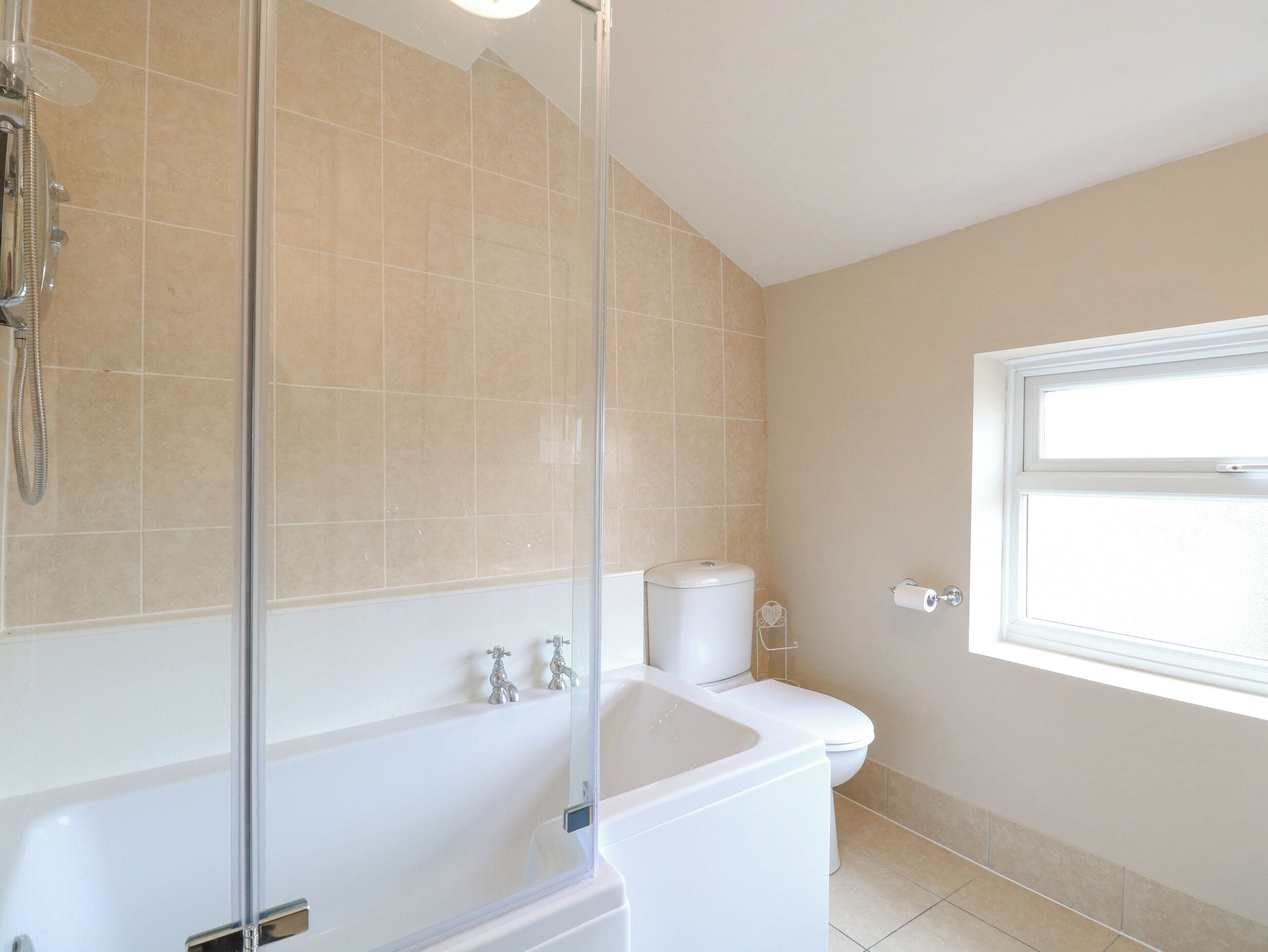 A bathroom with a glass-enclosed shower, a white bathtub, and a toilet.