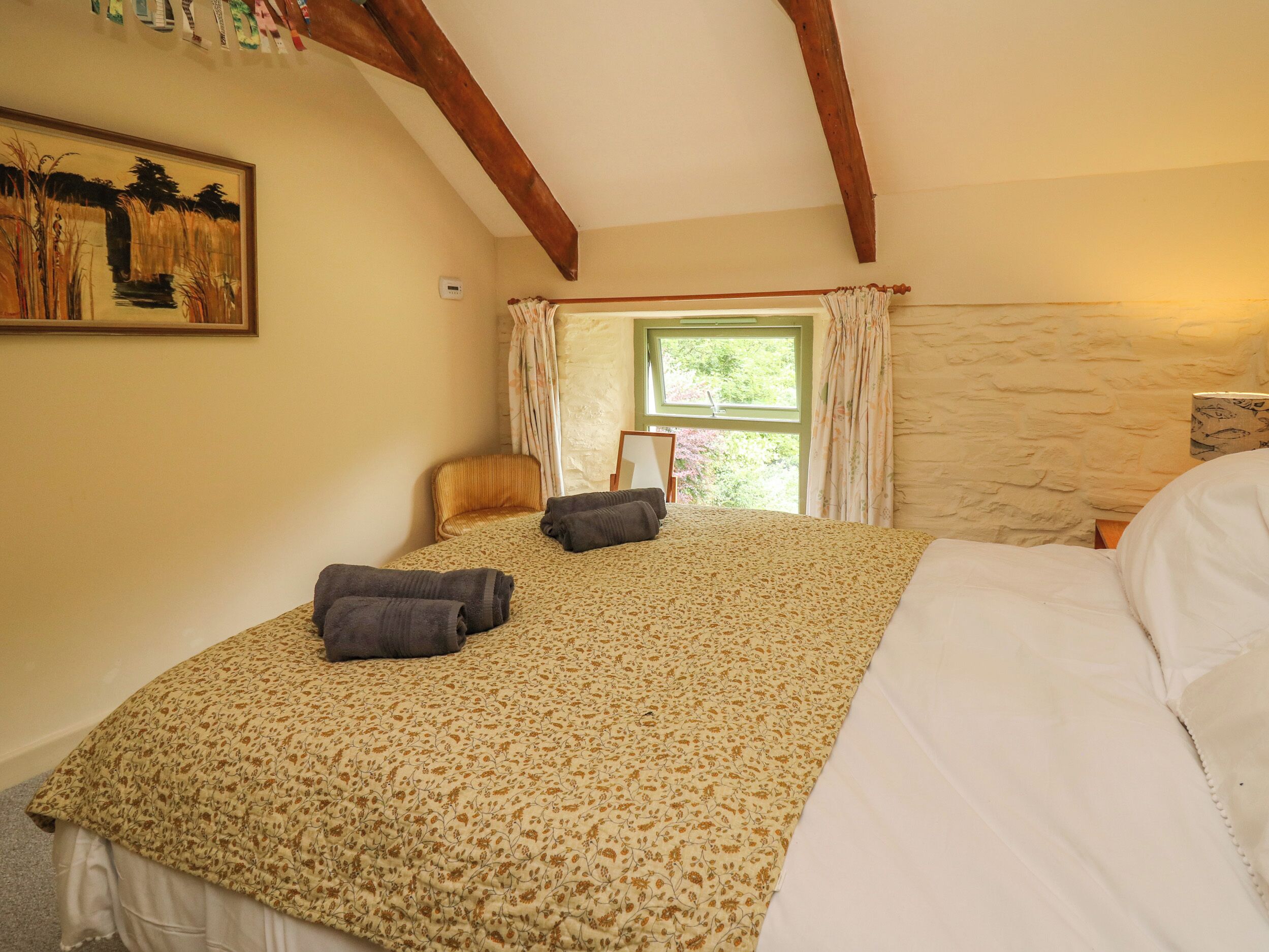 A bedroom with a large bed, a chair, a window with curtains, and a painting on the wall.