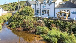 A coastal building with a fish logo, outdoor seating, and a stream nearby. - Golygfa Rhiw (Pwllheli)