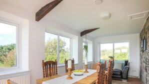 A dining area with a wooden table, chairs, and a view of the outdoors. - Golygfa Rhiw (Pwllheli)
