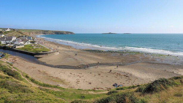 A coastal town with a beach, houses, and a clear sky. - Golygfa Rhiw (Pwllheli)