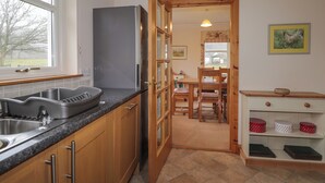 A kitchen with wooden cabinets, a built-in oven, and a large window. - Tigh na Drochit (Kyle)