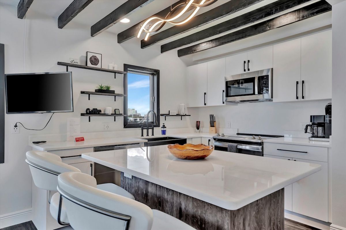 A modern kitchen with white cabinetry, a large island, and a built-in microwave.