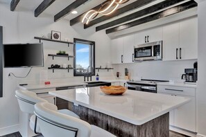 A modern kitchen with white cabinetry, a large island, and a built-in microwave. - Luxury Clearwater Beach: Waterfront Heated Pool (Clearwater)