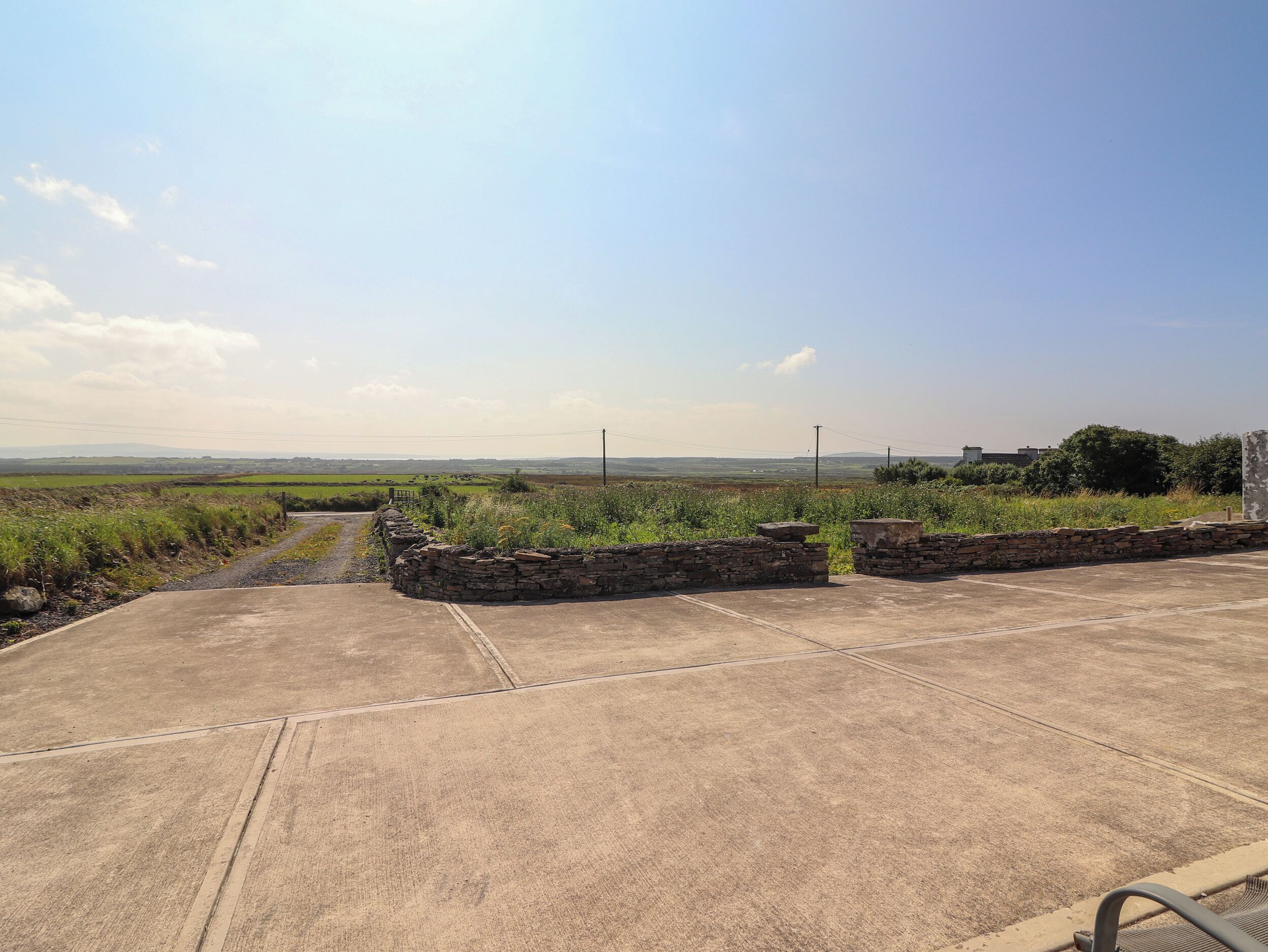 A paved area with stone walls and a rural landscape in the background.