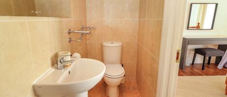 Un baño con lavamanos blanco, inodoro y zona de ducha.