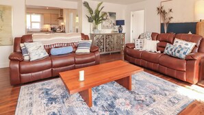 A spacious living room with two brown leather sofas, a wooden coffee table, and a patterned rug. - Cottage View (Carrigaholt)