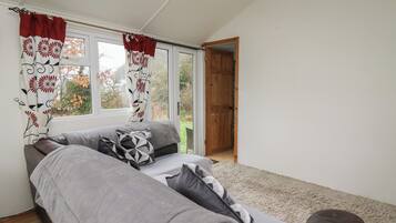 A room with a sofa, patterned curtains, and a view of the outdoors.