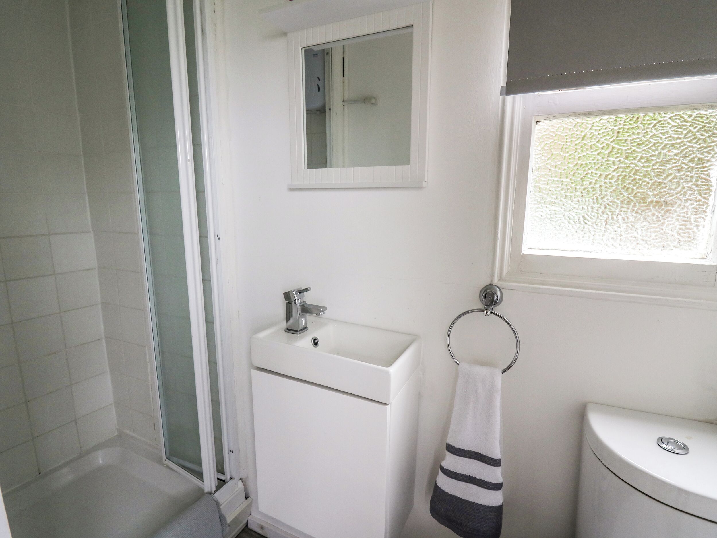 A bathroom with a shower, sink, and toilet.