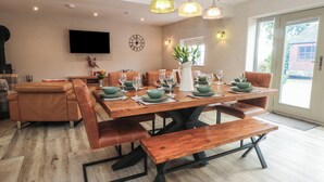 A dining area with a wooden table set for six, surrounded by leather chairs. A bench is placed in front of the table. - Small Lane Barn (Stoke-on-Trent)