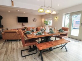 Un comedor con una mesa de madera dispuesta para seis personas, rodeada de sillas de cuero. Una banca se encuentra frente a la mesa.