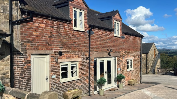 A two-story brick house with a front door, a small window, and a staircase leading to a second-floor window. - Small Lane Barn (Stoke-on-Trent)