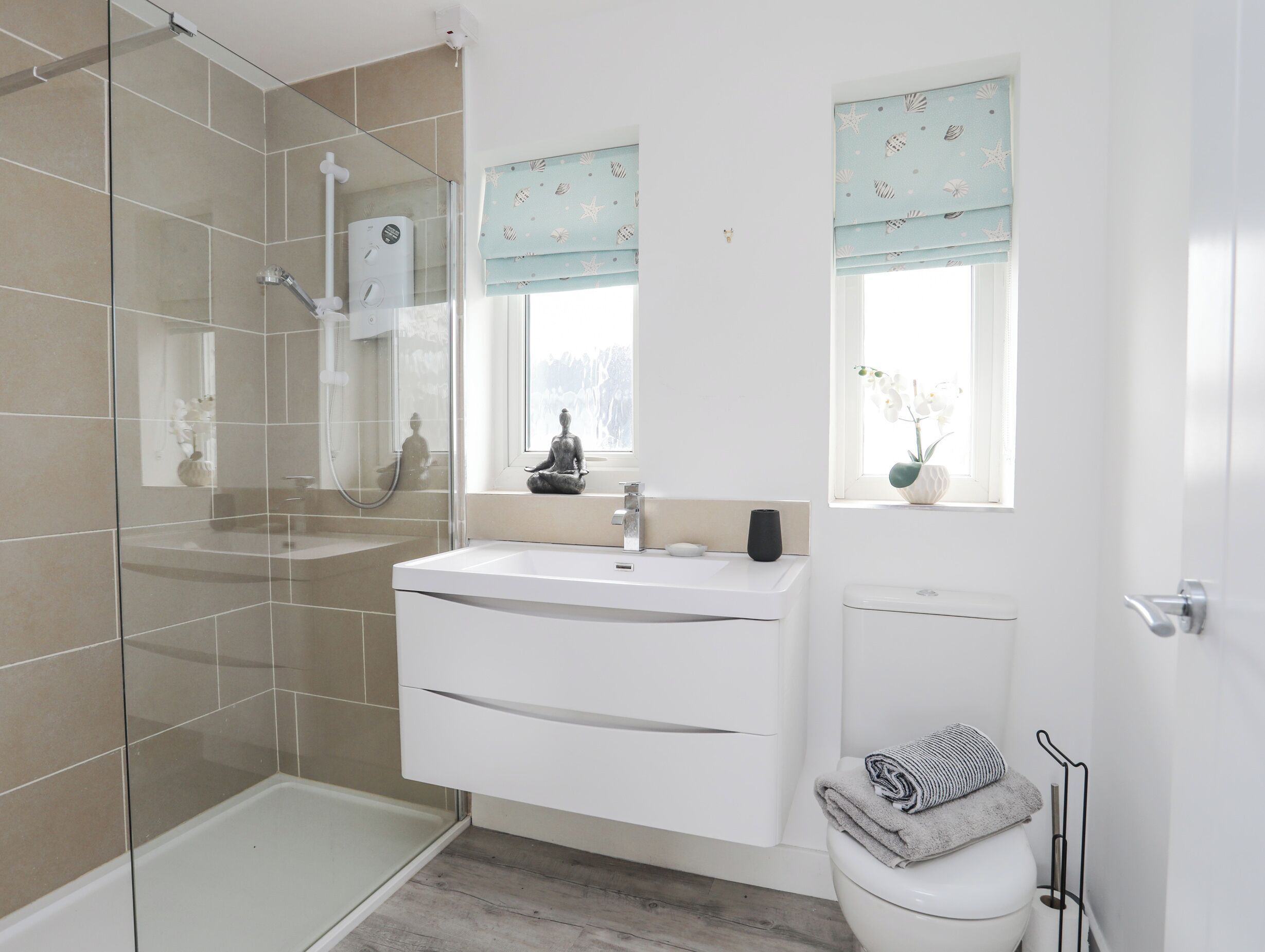 A modern bathroom with a glass shower enclosure, a white sink with a vanity, and a toilet.