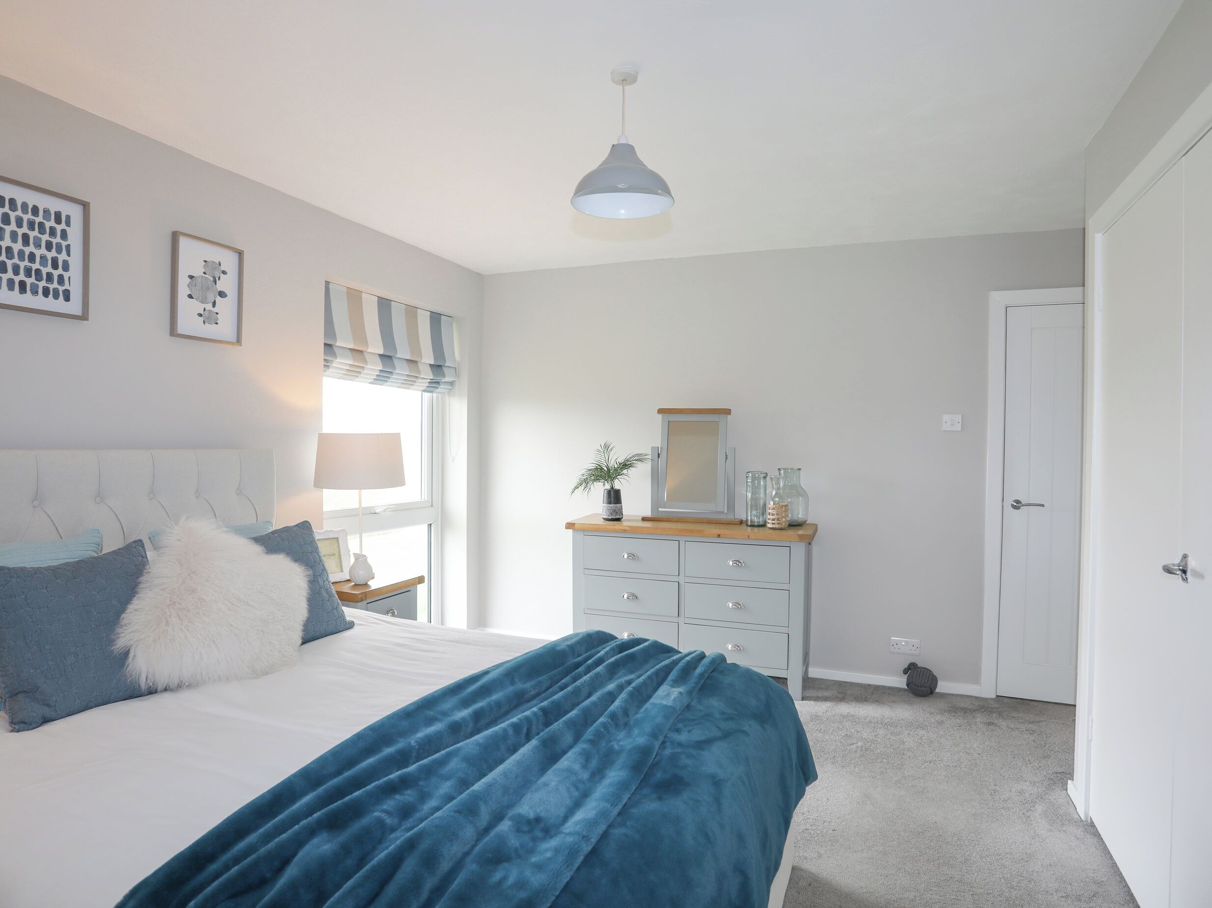 A bedroom with a bed, a dresser, a mirror, and a door.