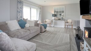 Ein Wohnzimmer mit Sofa, Sesseln, Kamin und Fernseher.