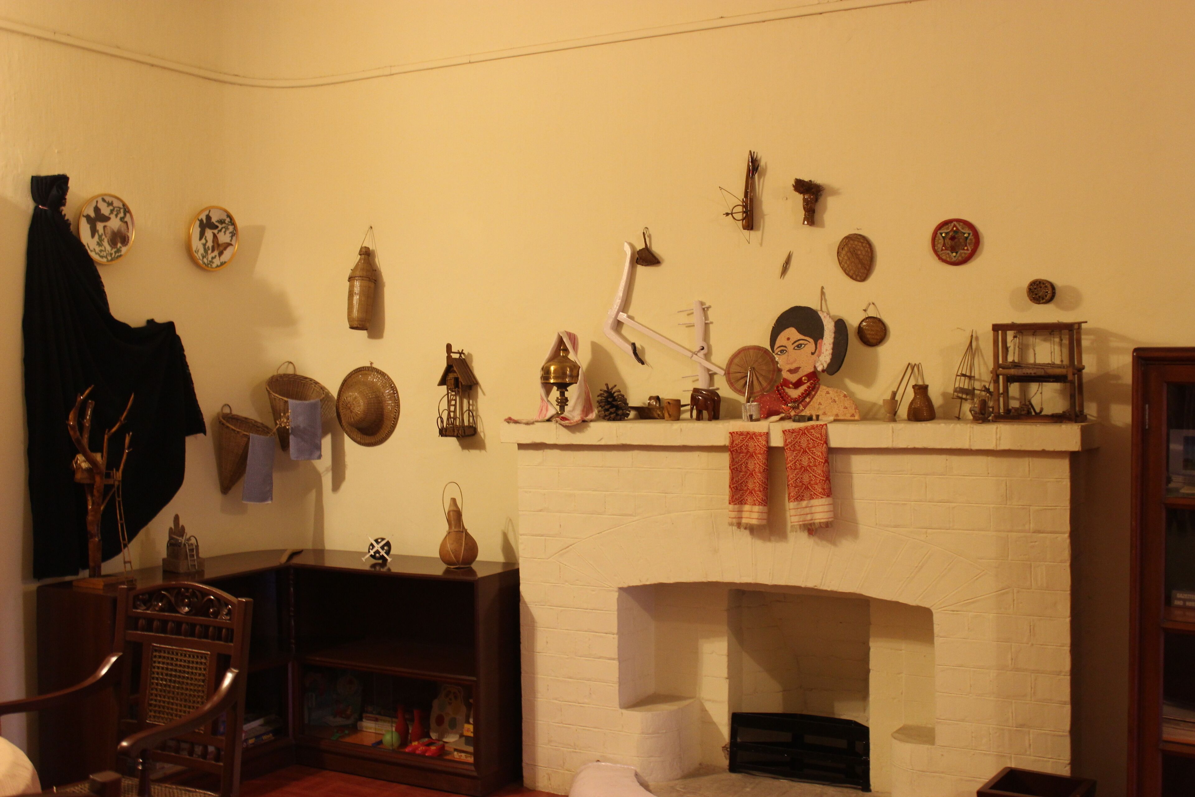 A cozy room with a fireplace, shelves with decorative items, and a chair.