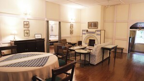 A hotel room with a dining table, chairs, a sofa, a fireplace, and a bed.