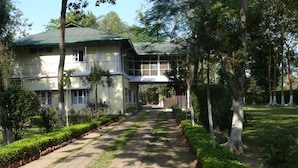 A two-story building with a green roof, surrounded by well-maintained gardens and trees.