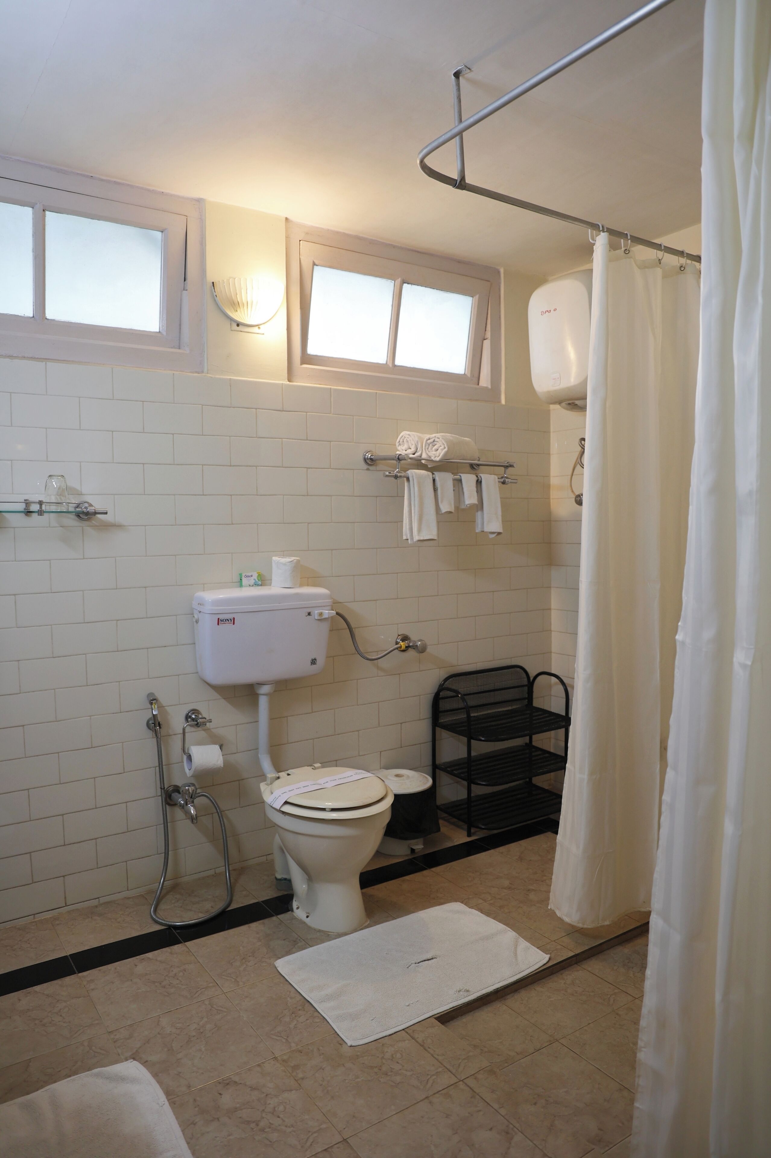 Une salle de bain équipée de toilettes, d’une douche et d’un porte-serviettes.