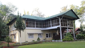 A two-story house with a green roof, large windows, and a garden in front.