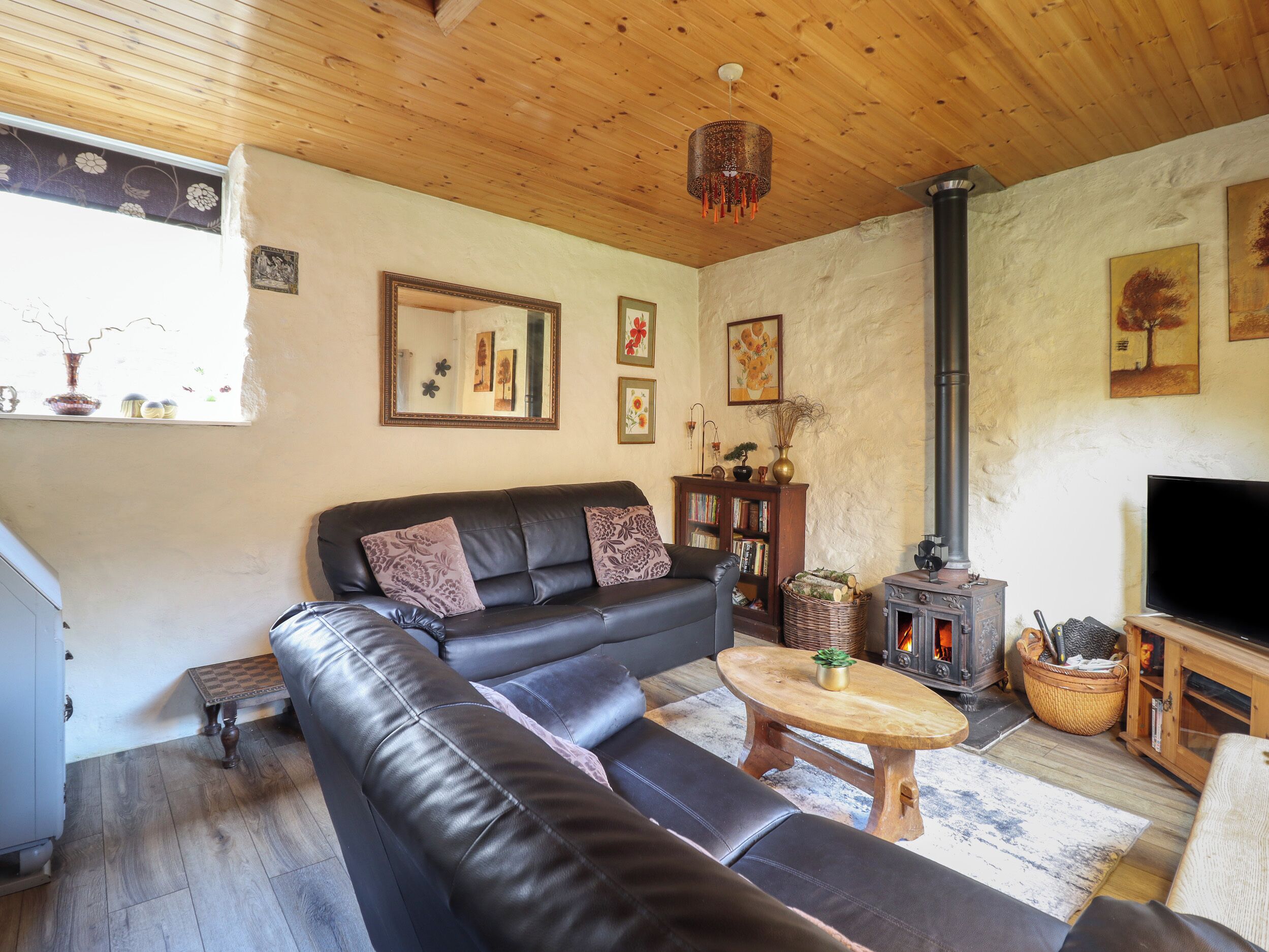 A cozy living room with a leather sofa, a wooden coffee table, a fireplace, and a bookshelf.