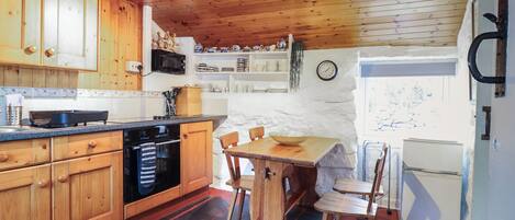Una cocina con armarios de madera, una estufa, un microondas y un comedor con mesa y sillas.