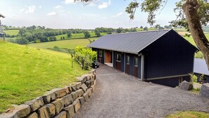 A building with a gravel driveway leading to a metal roofed entrance.
