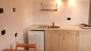 A compact kitchen with a sink, a small refrigerator, and wooden cabinets. - Agriturismo Prisma: Double Room with Private Bathroom (Villa Vergano)