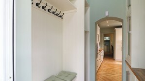 Un couloir avec un banc, un porte-manteau et, au fond, un coin cuisine.