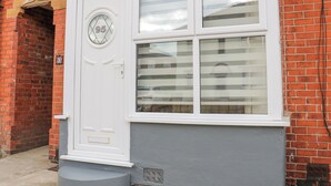 Une porte blanche avec un vitrage, une plaque d’immatriculation et un mur gris.