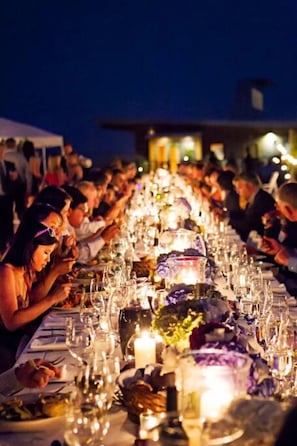A long dining table set with multiple candles and glasses, suggesting a formal dining event.