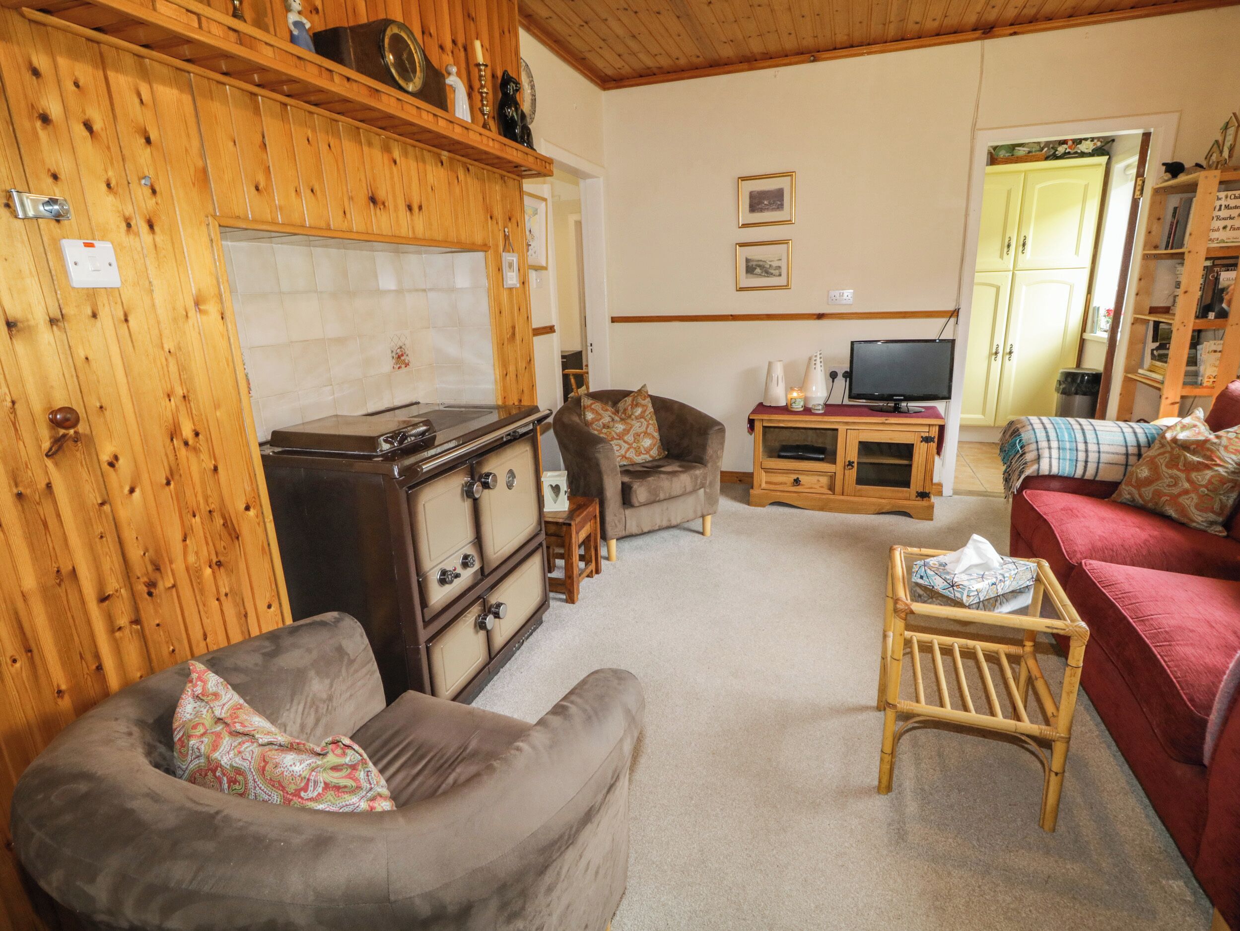 A cozy living room with a wooden cabinet, a television, a sofa, and a small table.