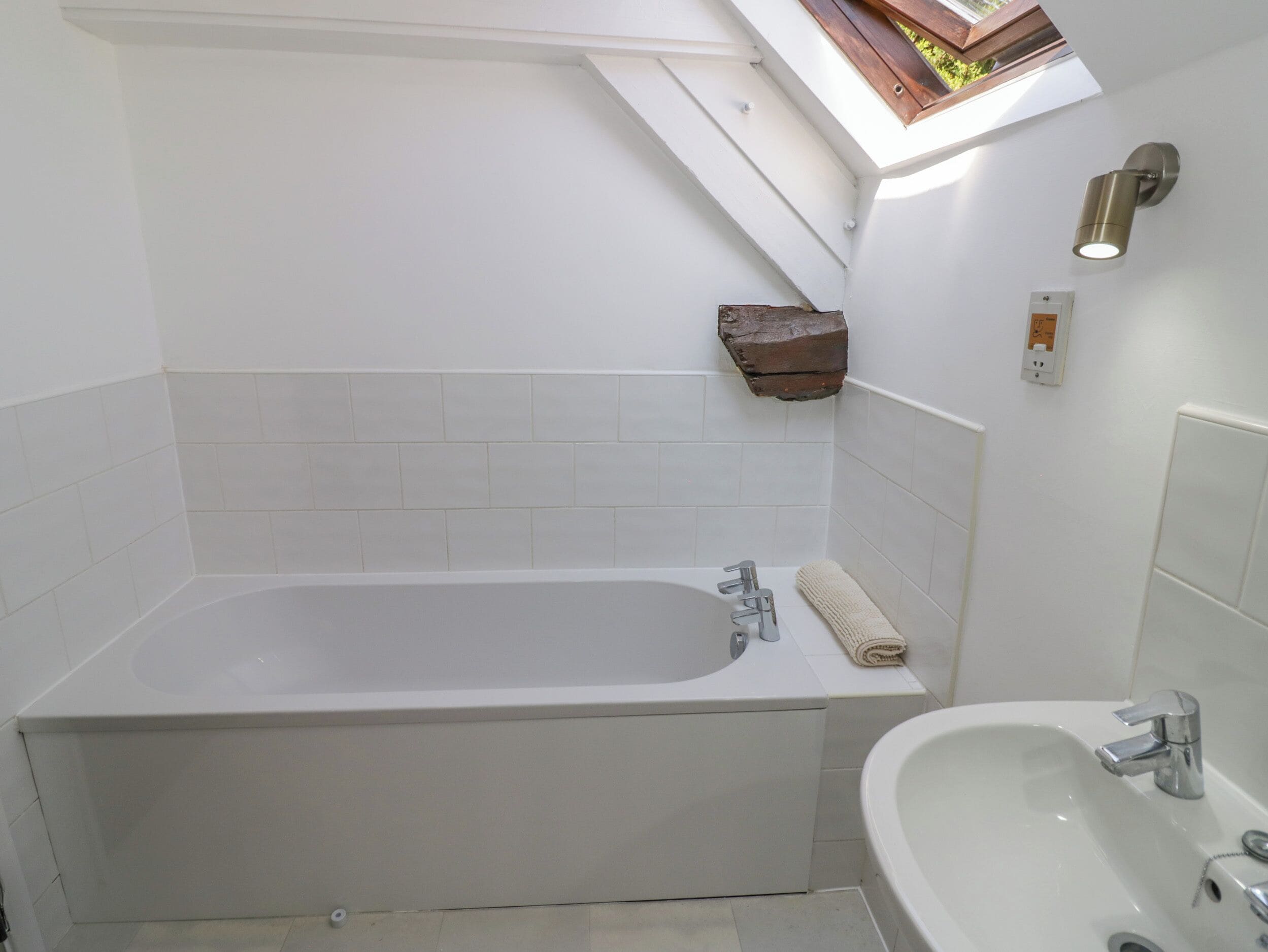 A modern bathroom with a freestanding bathtub, a sink, and a skylight above.