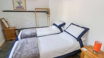 A bedroom with two beds, a wooden nightstand, a lamp, and a framed picture on the wall.