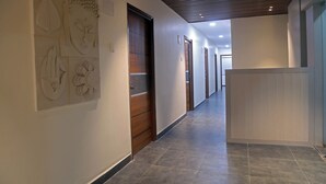 En moderne gang med en trædør, en receptionsdisk og billedkunst på væggene.